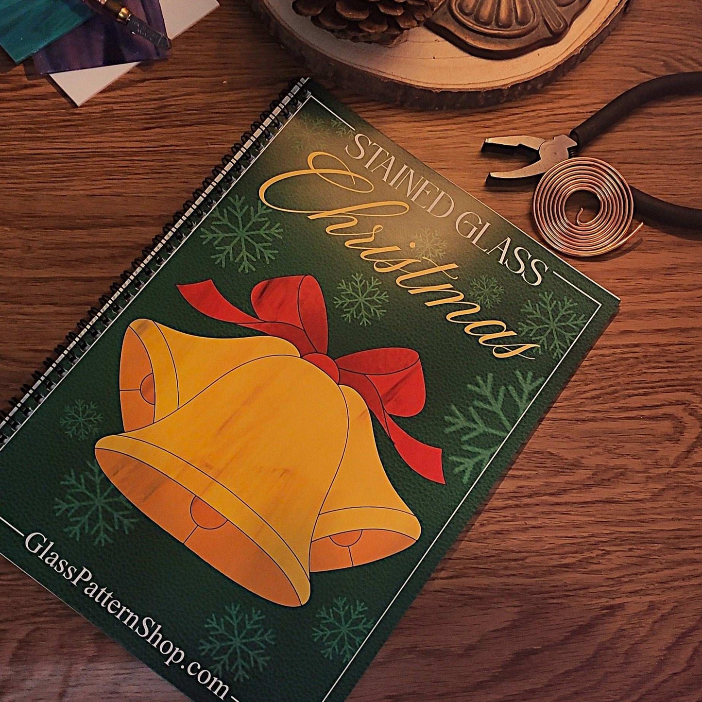 Cover of the Christmas Stained Glass Pattern Book featuring festive designs like Christmas trees, pinecones, and snowmen for stained glass art.